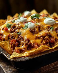 a close up of a plate of nachos with cheese and meat on it