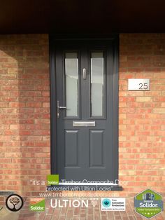 the front door is painted black and has two glass panels on it, along with a brick wall