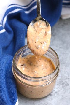 a spoon full of peanut butter on top of a jar