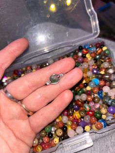 a person holding a ring in their hand surrounded by beads