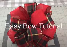 a bow that has been made with red and black plaid fabric, is sitting on top of a cutting board