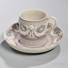 a cup and saucer on a plate with an ornate design around the rim,