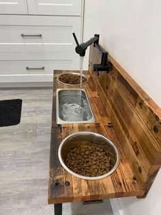 a wooden bench with two bowls filled with dog food on it and water running from the faucet