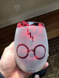 a hand holding up a wine glass with an image of harry potter glasses on it