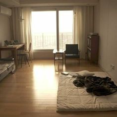 an empty room with a bed, desk and television in the corner near a sliding glass door