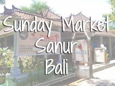 a sign that says sunday market samur ball in front of a building with trees and bushes