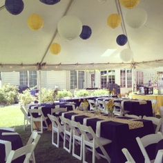 tables and chairs are set up under a tent with paper lanterns hanging from the ceiling