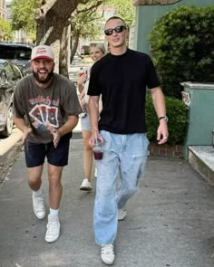 two men are walking down the street with one man in black shirt and blue jeans