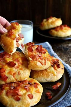 a person is cutting into some pizzas on a plate next to a glass of milk