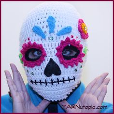 a person wearing a crocheted skull mask with flowers on their head and hands