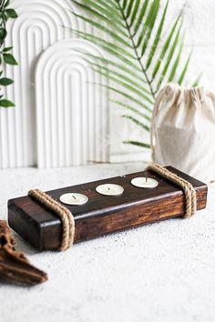 a wooden candle holder sitting on top of a white table next to a potted plant