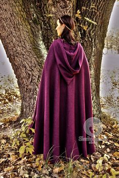 a woman standing in front of a tree with a purple cloak on her shoulders and back