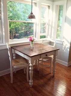 a wooden table sitting in front of two windows