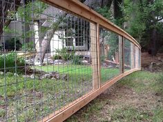 a fenced in area with grass and trees next to a house on the other side