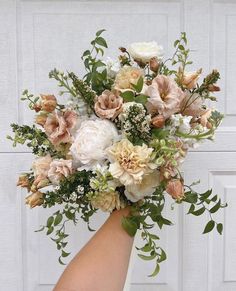 a woman's hand holding a bouquet of flowers in front of a white door