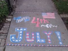 the sidewalk has chalk writing on it and an american flag, umbrellas, and stars