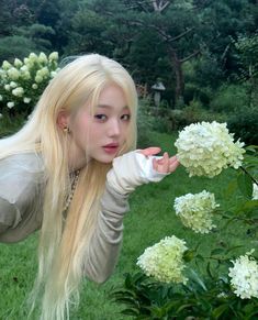 a woman with long blonde hair is posing in front of some white hydrangeas