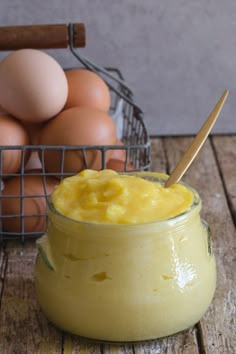 a glass jar filled with yellow liquid next to eggs