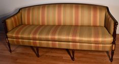 a striped couch sitting on top of a hard wood floor next to a white wall