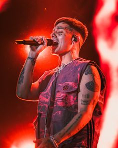 a man with tattoos and piercings on his arm singing into a microphone at a concert