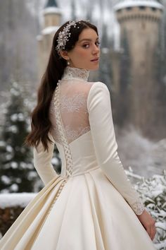 a woman wearing a white dress with long sleeves and a tiara on her head