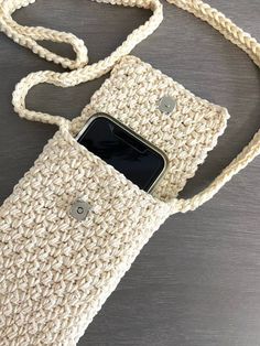 a cell phone in a crocheted bag on a table