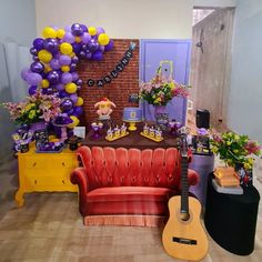 a room decorated with balloons, flowers, and a guitar on a table in front of a brick wall