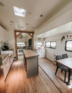 a kitchen and dining area in a small home with wood floors, white walls and cabinets