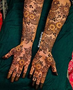 two hands with henna tattoos on them, one is showing the intricate pattern and the other has flowers