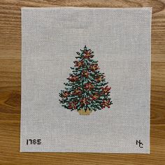 a cross stitch christmas tree with red berries on the top and green leaves on the bottom