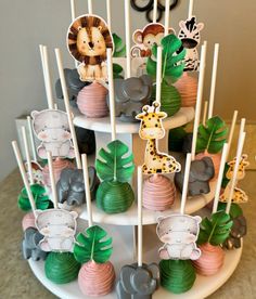 a tiered cake with cupcakes decorated as animals and giraffes