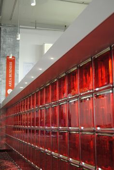 red glass tiles on the side of a wall in an office building with signs hanging from the ceiling