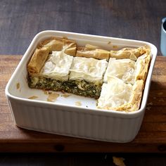 a casserole dish with spinach and cheese in it on a cutting board