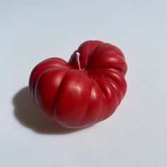 a red tomato sitting on top of a white table