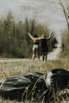 two people walking in the grass near trash bags