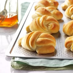 freshly baked rolls on a baking sheet with honey in the background