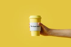 a person's hand holding a yellow coffee cup with the words that food finds on it