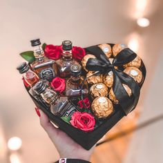 a person holding a heart shaped box filled with liquor and chocolate covered candies in it