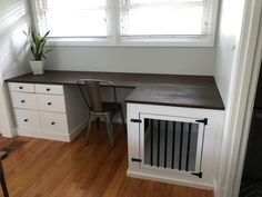 an empty room with a desk, chair and dog door on the floor in front of two windows