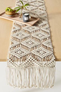 a crocheted table runner on a wooden table with two candles and a tray