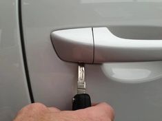 a hand holding a car door handle with a key in it