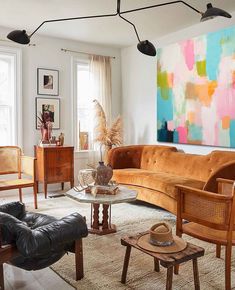 a living room filled with lots of furniture and paintings on the wall above it's windows