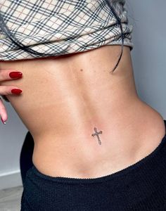 a woman with a cross tattoo on her lower back