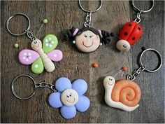 four different key chains with ladybug, snail and flower charms on them sitting on a wooden surface