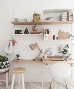 a white room with shelves filled with books, plants and other things on top of them