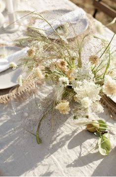 the table is set with white plates and flowers