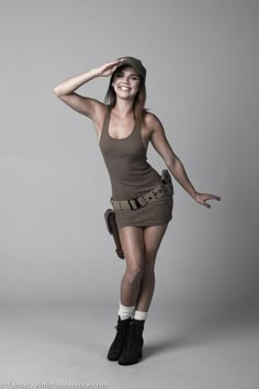 a woman in a short skirt and tank top posing for a studio photo with her arms behind her head