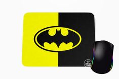 a batman mouse pad with a black and yellow bat symbol on the side, next to a computer mouse