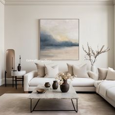 a living room filled with furniture and a painting hanging on the wall above it's coffee table