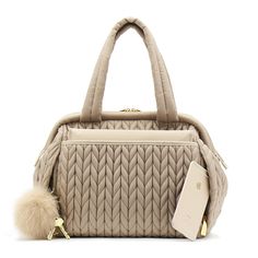 the beige handbag has a fur ball on it